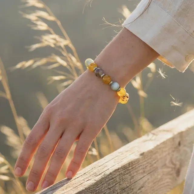 A honey-gold bracelet on a wrist among tall grass